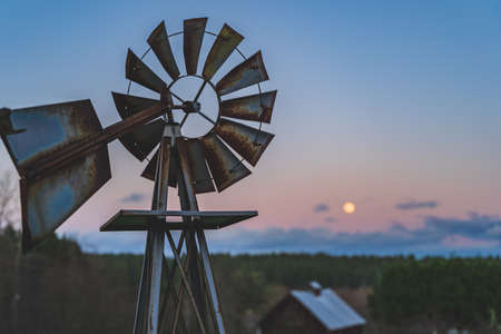 Dramatic Evening sky with yellow moon rising windmill silhouette foregroundの写真素材