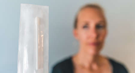 woman holds unopened PCR sars covid 19 nasal test swab to cameraの写真素材