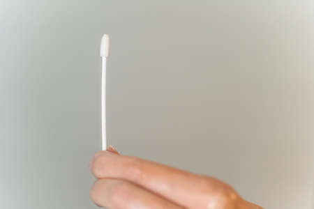 Hand holds Covid-19 PCR nasal swab against background with copy space