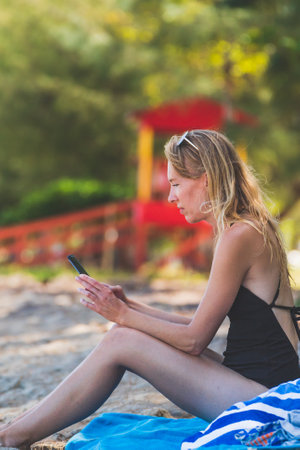 close up Woman using smartphone while vacationing on beachの写真素材