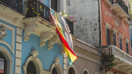 Weathered rainbow Gay Pride Flag hangs from balcony in Old San Juanのeditorial素材