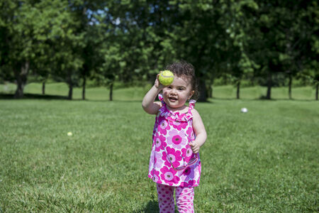 Little Girl Playing Ball in Grassy Parkの写真素材