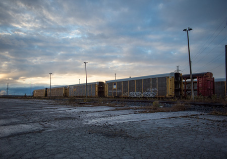 Graffiti Tags on Old Abandoned and Empty Train Box Cars in Railway Yard at Dusk in Summerの写真素材