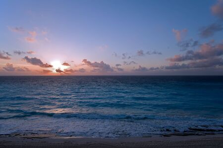 Sunrise in Cancun Mexico with sun rays coming through the cloudsの写真素材