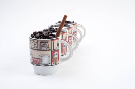 Coffee mugs filled with coffee beans and cinnamon stickの写真素材