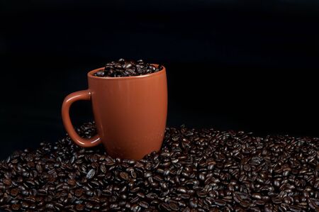 cup of coffee beans with cup on top of coffee beansの写真素材