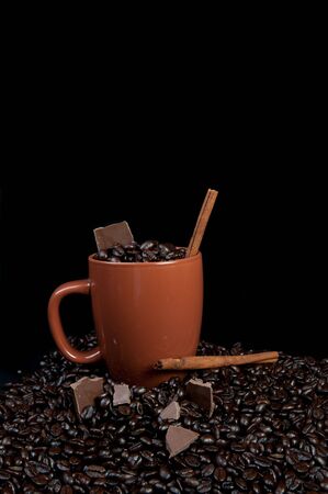 Coffee mug with coffee beans, cinnamon sticks and chocolateの写真素材