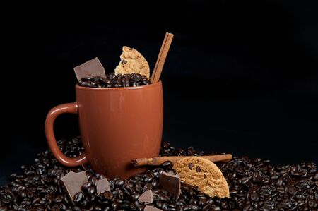 Coffee mug with coffee beans, cinnamon sticks and chocolateの写真素材