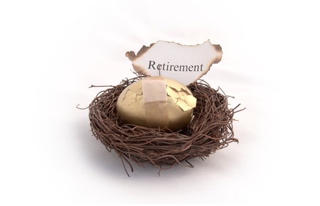 A golden egg sitting in a birds nest with a  piece of paper that reads retirement on it burning. Representing your savings going up in smokeの写真素材