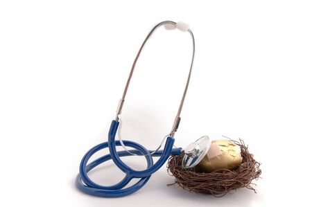 Golden nest egg with cracks and bandage over the egg and a stethoscope checking the health of the eggの写真素材