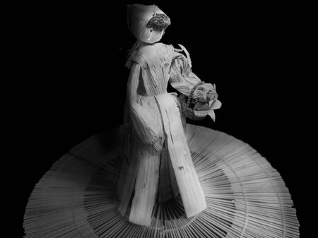 Woman made with recycled corn husks, with an old peasant look carrying a basket with flowers, in black and whiteの写真素材