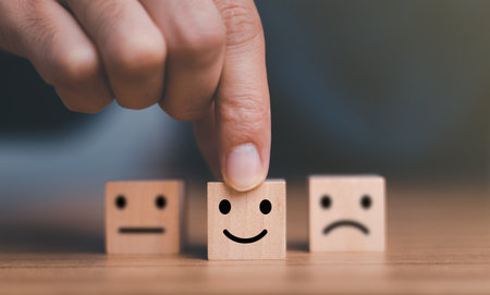 Close up customer hand choose smile face and blurred sad face icon on wood cube, Service rating, Customer service evaluation and satisfaction survey concepts.の写真素材
