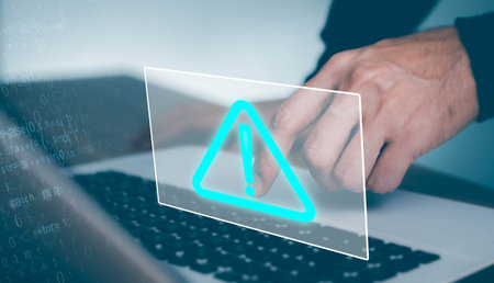 Businessman working on laptop computer at office with exclamation alarm caution warning notification mark Sign, computer virus detectedの写真素材