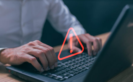 Businessman using computer laptop with triangle caution warning sing for notification error and maintenance concept.の写真素材