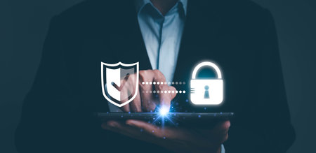 Cyber security. Business, technology, internet and networking concept. Young business man working on his laptop in the office, select the icon security on the virtual display.の写真素材