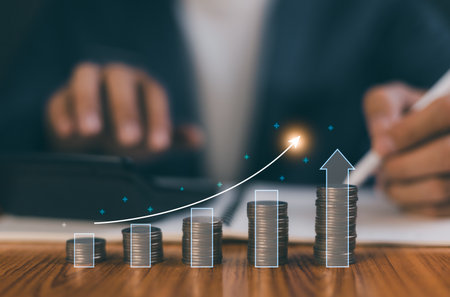 Businessman using calculator and financial planning with growing coin stack and digital arrow graph showing profit and business success. Concept of investment, saving, management and economic growth.の写真素材