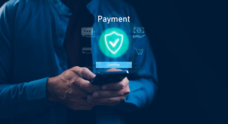 Businessman using a smartphone for secure online payment, featuring a glowing shield icon and digital transaction symbols. Ideal for fintech, e-commerce security, and mobile banking concepts.の写真素材