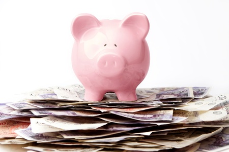 Piggy bank on stack of British Poundsの写真素材