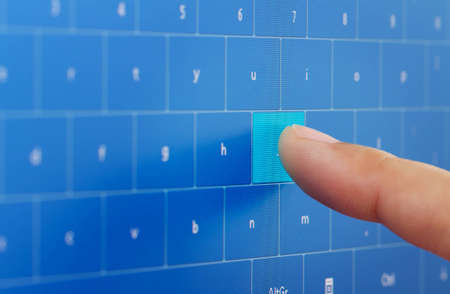 Human hand typing on digital keyboard at touch screenの写真素材
