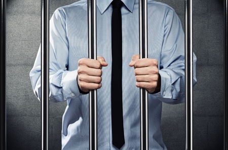 Young corrupted businessman behind the prison barsの写真素材