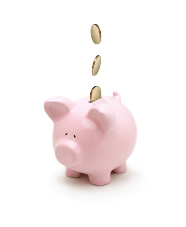 Golden coins falling into a piggy bank isolated on white backgroundの写真素材