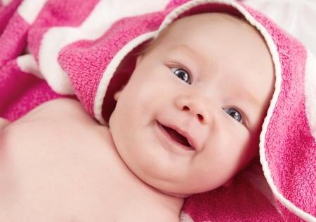 Adorable baby girl in pink blanket smilingの写真素材
