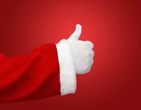 Santa Claus hand showing thumbs up over red background with copy spaceの写真素材