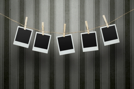 Five blank photographs hanging on a clothesline over vintage striped background with clipping path for the inside of the framesの写真素材