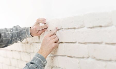 Home improvement, close up of a specialist installing brick wall tiles with copy spaceの写真素材