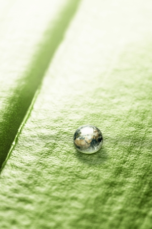 Environmental conservation, small planet earth in water drop on a leaf with copy spaceの写真素材