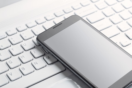 Close up of blank mobile phone on the laptop with clipping path for the screenの写真素材