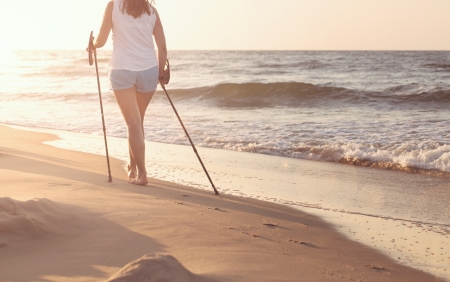 Close up of female nordic walking on a beach at the sunsetの写真素材