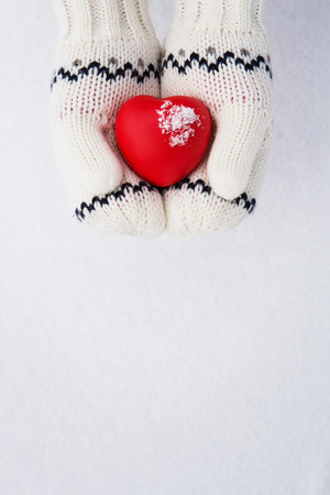 Winter background, close up of little girls hands holding red rubber heart with copy spaceの写真素材