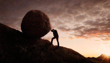 Business concept, Young businessman pushing large stone uphill with copy spaceの写真素材