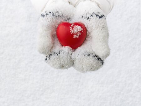 Winter background, close up of little girl hands holding red rubber heart with copy spaceの写真素材