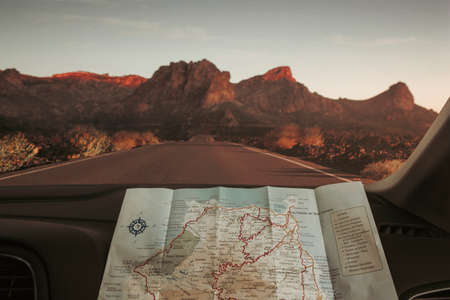 Travel concept, reading map on an empty road at the sunsetの写真素材