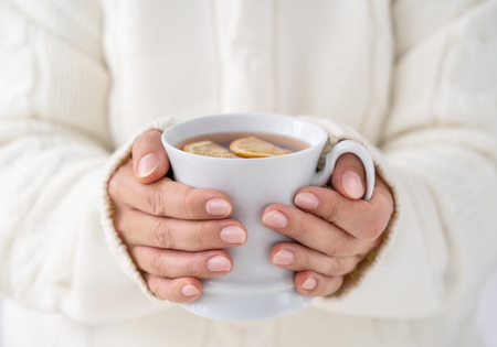 Close up of female hands holding cup of hot tee with copy space の写真素材