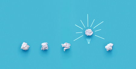 Great idea concept. Crumpled paper as a lightbulb isolated on blue background with copy spaceの写真素材
