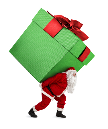 Santa Claus carrying huge christmas gift isolated on white backgroundの写真素材