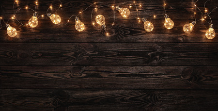 Empty, dark wooden background illuminated by retro light bulbs, with copy spaceの写真素材