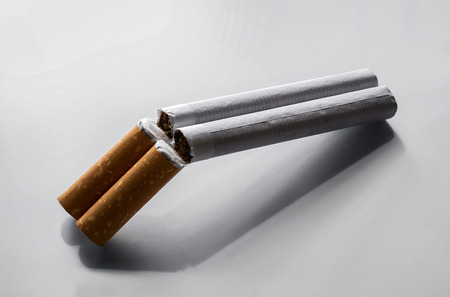 Quit smoking concept, two cigarettes as a double barrel rifle over gray background with copy spaceの写真素材