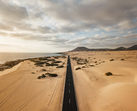 Aerial view of an empty road through the dunes at the sunrise with copy spaceの写真素材