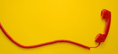 Red vintage telephone handset isolated on yellow background with copy spaceの写真素材