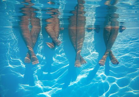 Close up of friends, family legs underwater in the swimming pool with copy spaceの写真素材