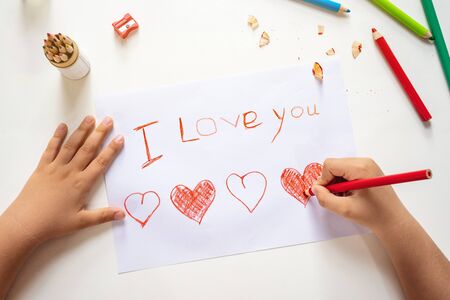 High angle view of childs hands drawing I love you sign on the paper sheetの写真素材