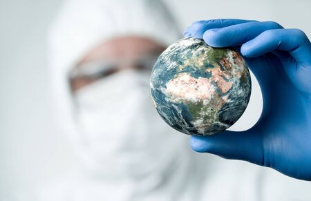 Pandemic concept, close up of scientist holdnig and analyzing planet earthの写真素材