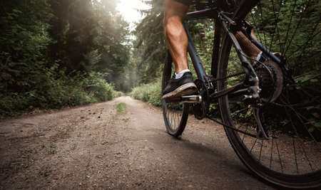 Close up of a biker riding a bike through the forest roadの写真素材