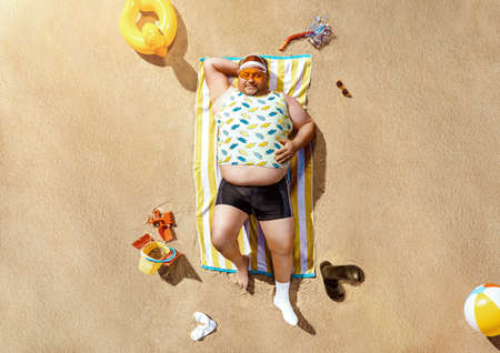 High angle view of funny overweight tourist resting on the beach