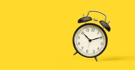 Close up of alarm clock isolated on yellow background with copy spaceの写真素材