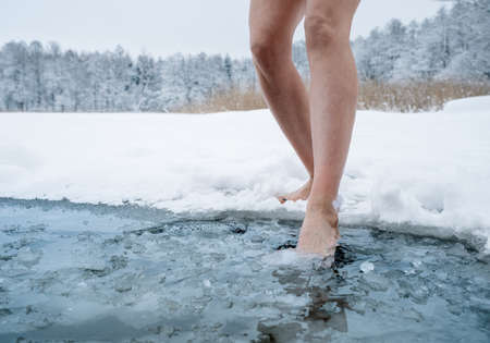 Close up of female legs getting into ice cold waterの写真素材